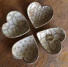 four heart shaped dishes sitting on top of a wooden table