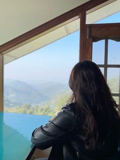 a woman sitting at a table looking out over the mountains from a room with a view