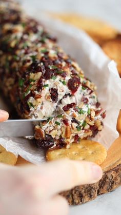 someone cutting up food with a knife on top of some crackers and other snacks