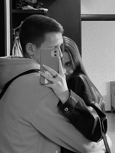 a man and woman taking a selfie with their cell phones in black and white