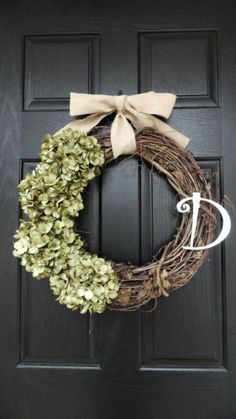 a wreath with the letter d on it and a bow hanging from the front door