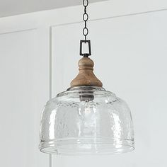 a clear glass light hanging from a ceiling fixture with a wooden beam and chain attached to it