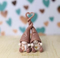 two small figurines sitting next to each other on top of a wooden table