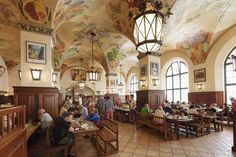 people sitting at tables in a restaurant with large murals on the walls and ceiling above them