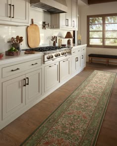 a large kitchen with white cabinets and wooden flooring on the walls, along with an area rug in front of the stove