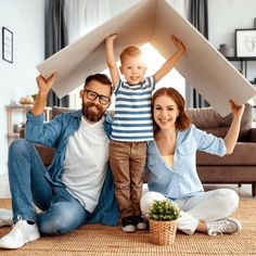 a man, woman and child are sitting on the floor in front of a cardboard airplane