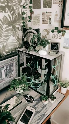 a computer desk with plants and pictures on the wall