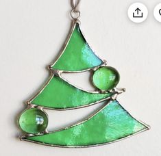 a green christmas tree ornament hanging on a white wall