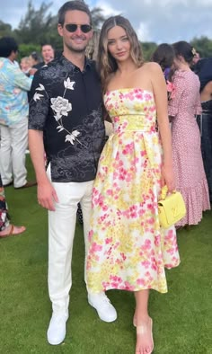 a man and woman standing next to each other on top of a grass covered field