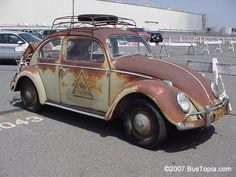 an old rusted out car parked in a parking lot