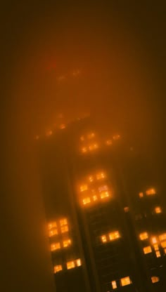 an image of some buildings in the fog with lights on at night and no one around them