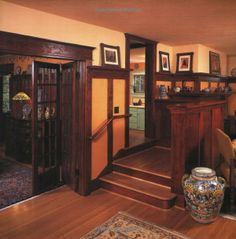 a living room filled with furniture and pictures on the wall next to a wooden staircase