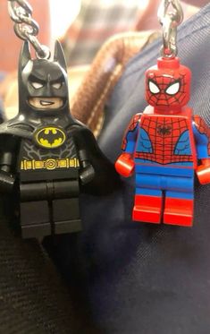 two lego batman and spider man keychains sitting on top of each other's purse