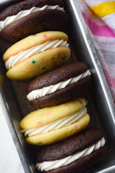 chocolate cookies with white frosting in a metal pan on a pink and yellow towel