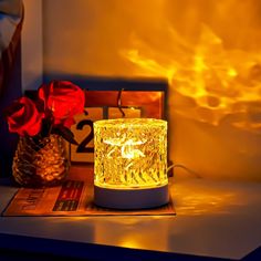 a lit candle sitting on top of a table next to a vase filled with red roses