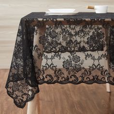 a black table cloth with flowers and leaves on it is sitting on a wooden floor