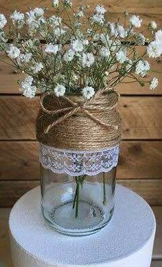 white flowers in a mason jar tied with twine on top of a cake stand