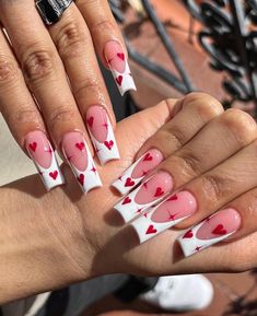 a woman's hand with pink and white hearts painted on it, holding up her nails