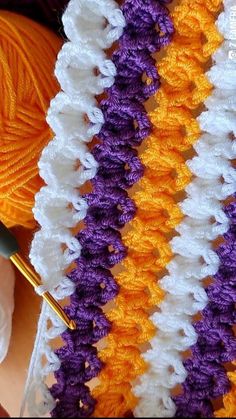 a crocheted blanket with yarn and knitting needles