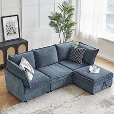 a living room with a blue sectional couch and pillows on the floor, next to a potted plant