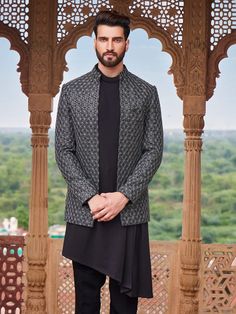 a man standing in front of a gazebo wearing a black and white jacket with geometric patterns on it