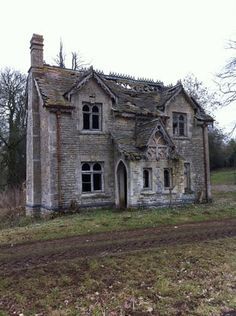 an old, run down brick house in the middle of a field with no grass