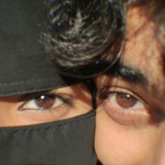 a close up of a person wearing a hat and covering his face with a cloth