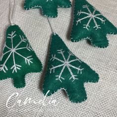 three green christmas trees are hanging on a white tablecloth with snowflakes and the words crochet written below them