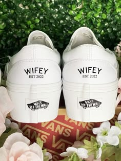 two white shoes with the words wife ests 2012 on them next to pink flowers