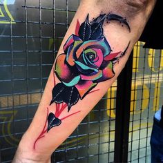 a colorful rose tattoo on the arm