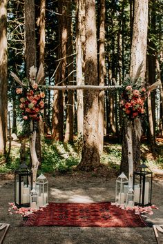 an outdoor ceremony setup with candles and flowers on the ground, surrounded by trees in the background