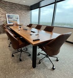 an empty conference room with chairs and a large wooden table in front of a window