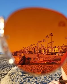 a person taking a photo through a mirror on the beach with palm trees in the background