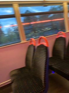 two empty seats sitting next to each other in front of a window on a train