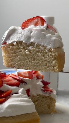 a piece of cake with white frosting and strawberries on the top is being lifted by a fork