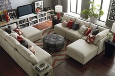 a living room filled with lots of furniture next to a large window covered in bookshelves