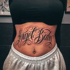 a woman's stomach with the words angel baby written on her lower back tattoo