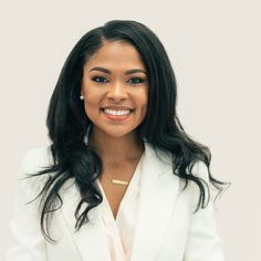 a woman in a white suit smiling at the camera with her hands on her hips