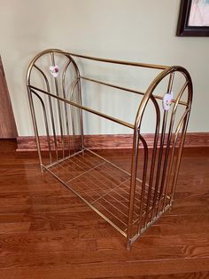 a gold metal magazine rack sitting on top of a hard wood floor