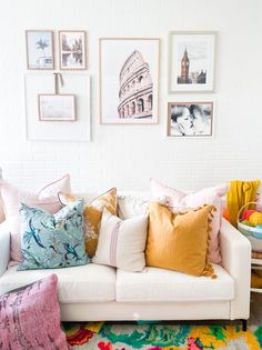 a living room filled with lots of pillows and pictures on the wall above it's couch