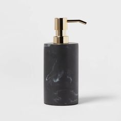 a black soap dispenser with a gold top on a white background,