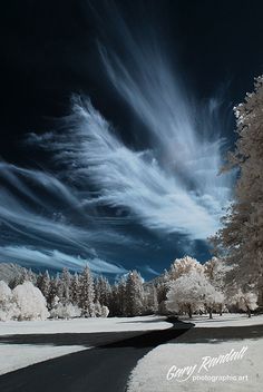 the sky is filled with clouds and snow as it sits in front of a tree