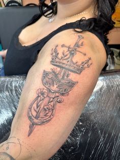 a woman with a crown and anchor tattoo on her arm is sitting in a chair