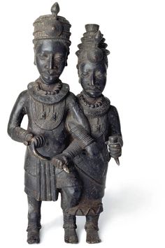 an old statue of two people holding something in one hand and another standing on the other