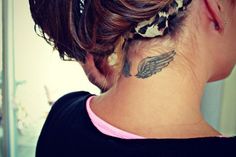 a woman with a tattoo on her neck is looking into the mirror and has an angel wing behind her ear