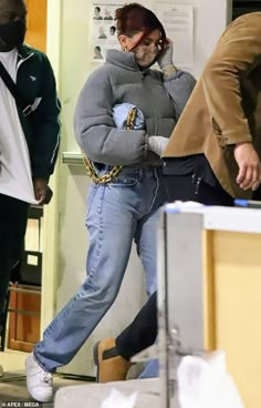 a woman in grey sweater and jeans walking through an office building with her hands on her hips