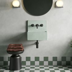 a bathroom with green and white checkered flooring next to a round mirror on the wall