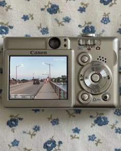 a digital camera sitting on top of a flowered cloth covered tablecloth next to a window