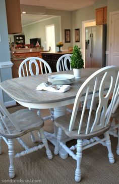 a dining room table with white chairs and a potted plant on top of it