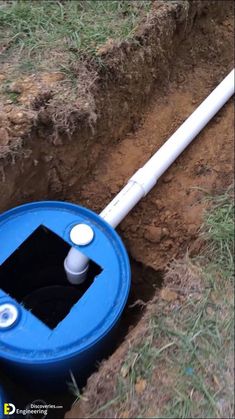 a blue and white pipe laying in the ground next to a hole that is filled with dirt